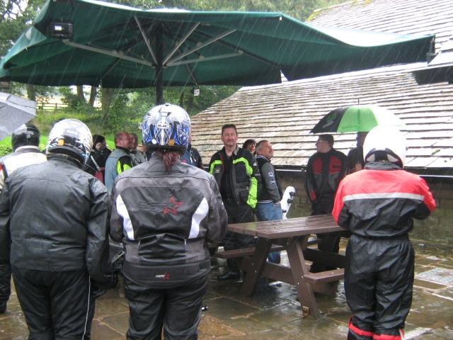 bikers in their waterproofs standing in the rain at rivington barn